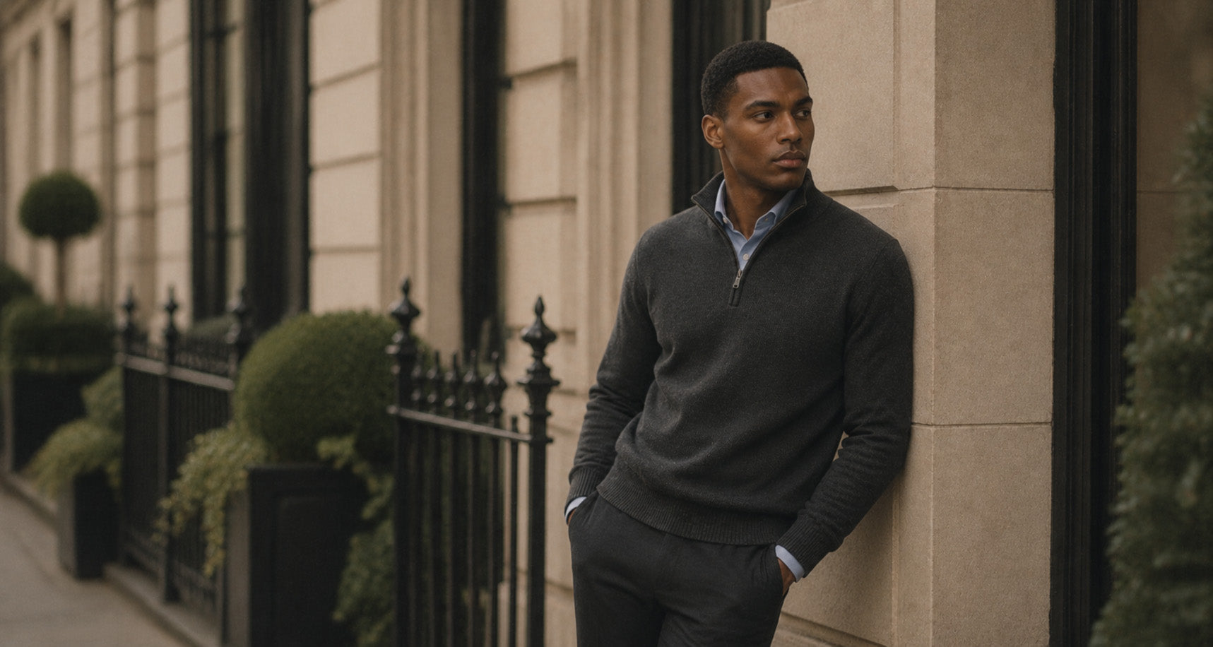 Man in a charcoal quarter-zip knit sweater leaning against a stone building, shop Knitwear at Malford of London
